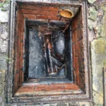 An open outdoor drain chamber being inspected by professionals providing the best drain unblocking in Brighton.